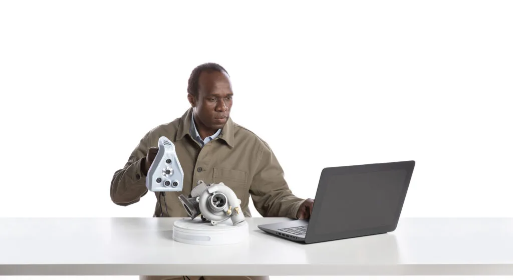 Operator scanning a turbocharger on a rotary table with a laptop running scanning software