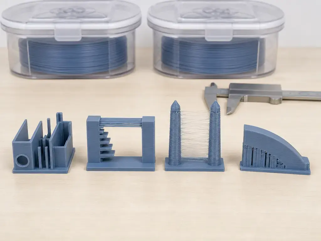 Four 3D-printed test samples are arranged with matching filament containers for a controlled comparison.